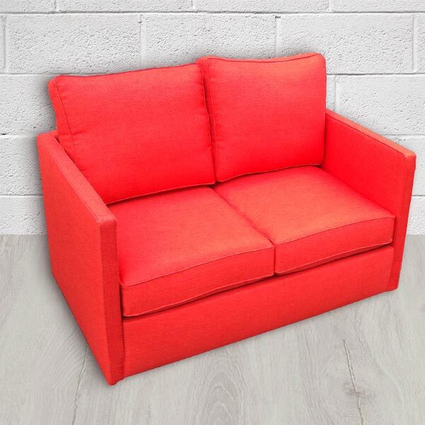 Petit canapé de trois quart. Le revêtement en cuir rouge apporte du dynamisme. Le design est moderne