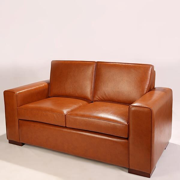 Canapé cuir marron de trois quarts. Les lignes sont droites ce qui apportent du caractère et appelle au confort.